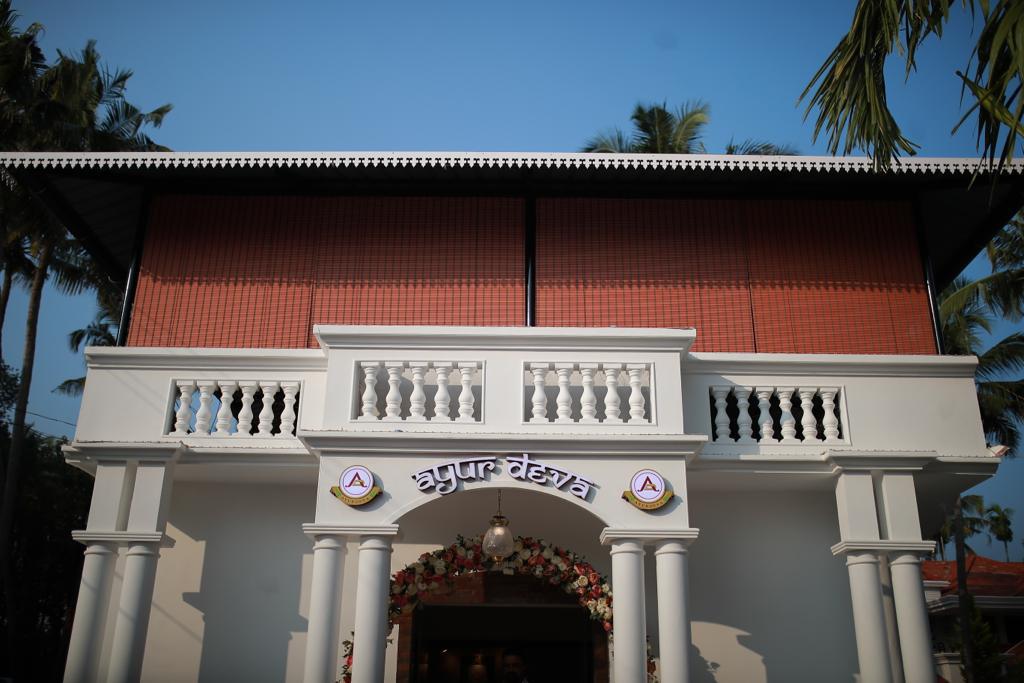 The Ayurdeva in-patient retreat building in Irinjalakuda, a white colonial-style Kerala house framed by palm trees